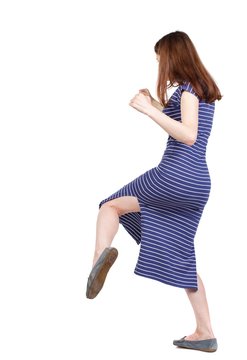 skinny woman funny fights waving his arms and legs. brunette in a blue striped dress fighting and kicking.