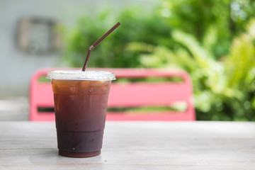 Glass of cold iced americano coffee on the wooden table.