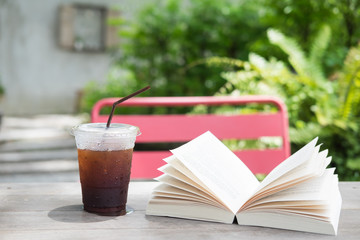 Glass of cold iced americano coffee on the wooden table wih open