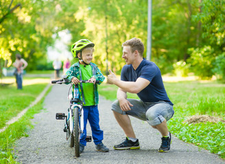 father talking with his son riding a bicycle - obrazy, fototapety, plakaty