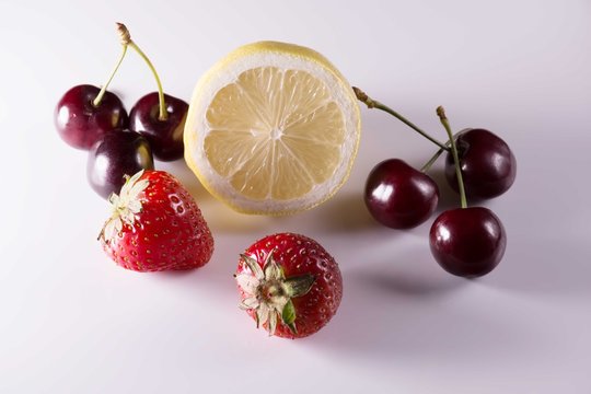 Lemon, cherries and strawberries on white background