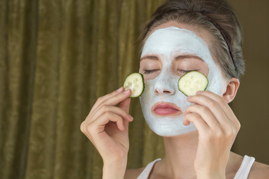 funny girl with mask holding two cucumber on the eyes