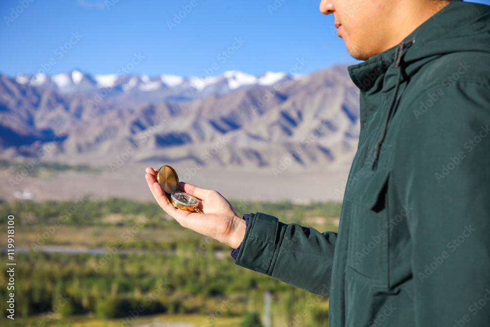 Wall mural young traveler looking at compass in himalaya mountain view background