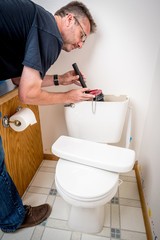 Plumber replaces parts in an old toilet