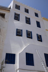 Fototapeta na wymiar Façade blanche avec fenêtres bleues et échelle en métal