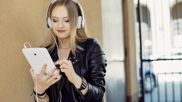 Punk girl listening music on headphones and using tablet, steadycam shot
