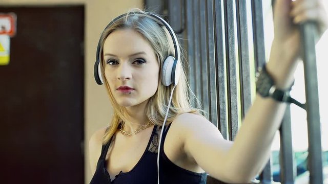 Punkg girl listening music on headphones and doing serious look to the camera

