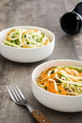 Carrot and zucchini noodles on a rustic wooden table

