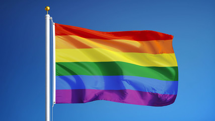 The gay pride rainbow flag waving against clean blue sky, close up, isolated with clipping path mask alpha channel transparency