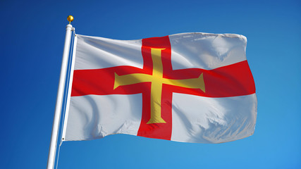 Guernsey flag waving against clean blue sky, close up, isolated with clipping path mask alpha channel transparency