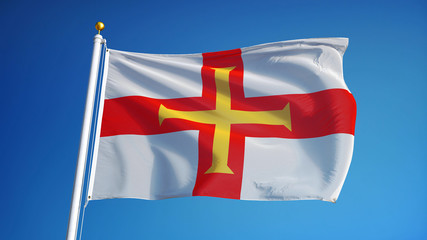 Guernsey flag waving against clean blue sky, close up, isolated with clipping path mask alpha channel transparency