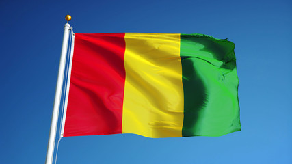 Guinea flag waving against clean blue sky, long shot, isolated with clipping path mask alpha channel transparency