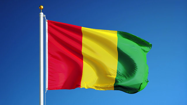 Guinea flag waving against clean blue sky, close up, isolated with clipping path mask alpha channel transparency