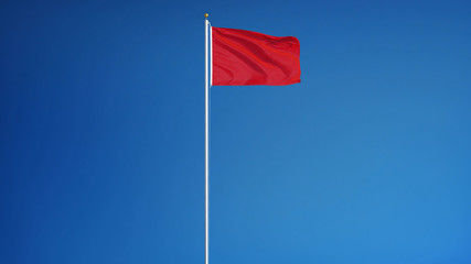 Fototapeta na wymiar Red flag waving against clean blue sky, long shot, isolated with clipping path mask alpha channel transparency