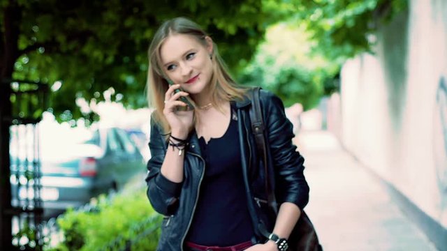 Punk girl standing on pathway and having a conversation on cellphone
