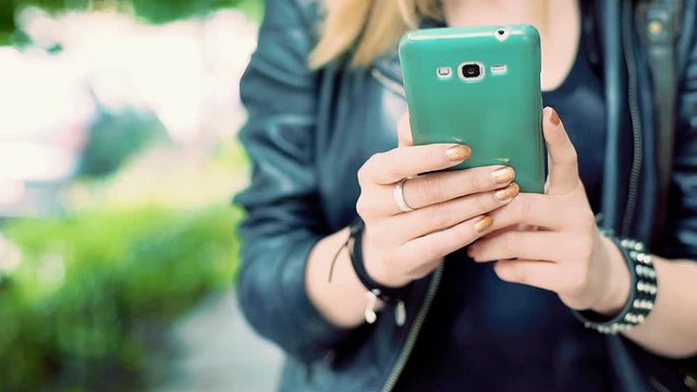 Punk girl holding smartphone and browsing internet on it, steadycam shot
