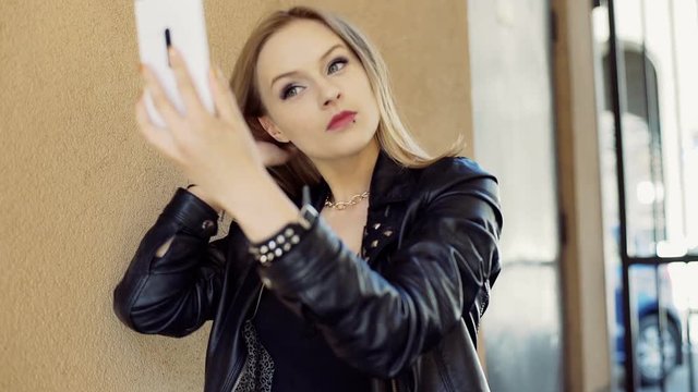 Punk girl looking to smartphone to check her appearance
