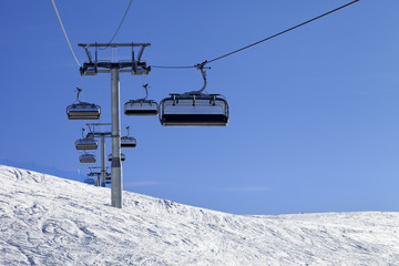 Ski-lift and off-piste slope in sun cold day