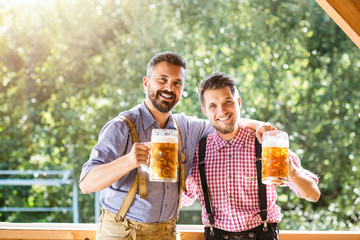 Men in traditional bavarian clothes holding mugs of beer
