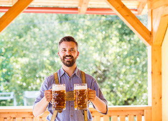 Man in traditional bavarian clothes holding mugs of beer