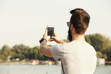 Handsome young man with beard taking selfie outdoor