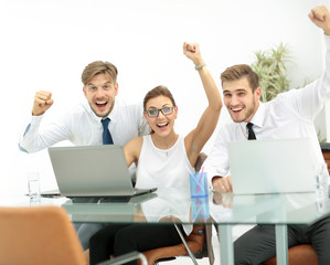 Team of three work colleagues with their arms raised in celebrat