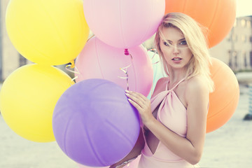 beautiful blonde happy woman with colorful pastel balloons in the city