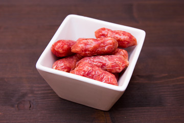 Small sausages on a square bowl on a wooden table