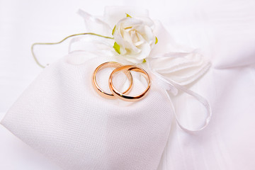 wedding rings on a white cloth bag with flower