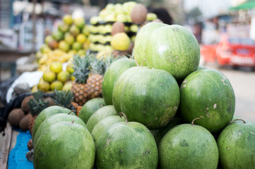 selling variety of fruits on shelves at the street market.