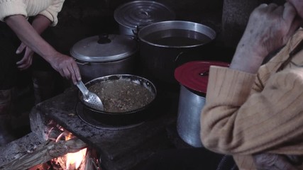 Women cooking on the firewood kitchen   around stewpots to make lunch. 4k