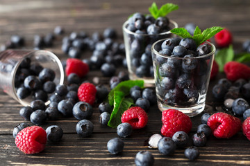 Blueberries, raspberries and mint at black wooden table.