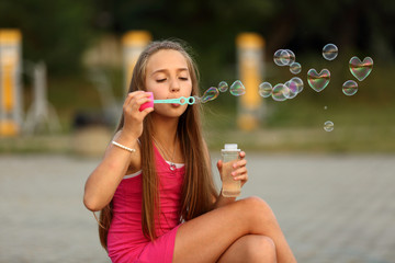 Fototapeta Śliczna dziewczynka puszcza bańki mydlane, serca. obraz