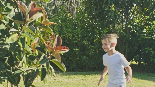Cute litle boy playing outdoors in the garden. Slow motion