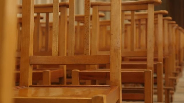Empty chairs in a row in the church close-up tilting 4K 2160p 30fps UltraHD footage - Wooden seats in cathedral empty without people slow tilt 4K 3840X2160 UHD video 