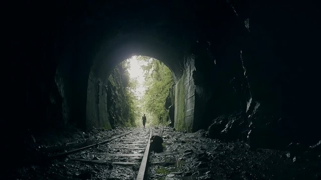 Woman getting into  the darkness over the rails of an abandoned train in inside of the ecuadorian jungle