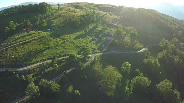 Aerial View, flight over green hills and countryside road and village houses