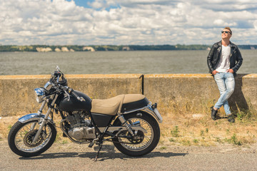 Fototapeta na wymiar Stylish guy standing next to his motorcycle