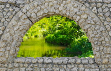 view on green nature through vintage old stones window