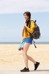 Smiling young woman with skateboard by beach