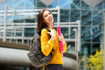 Smiling student holding backpack and notebook