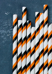 Striped drink straws for Halloween on a gray stone background