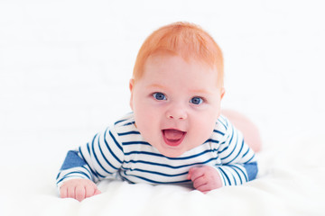 portrait of happy redhead baby boy lying on belly