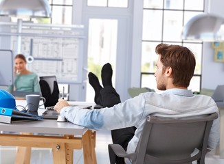 Architect designing with computer feet up on desk