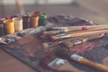 Photo of gouache and watercolor with brushes set in art studio. Oil paints smeared on palette