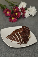 A slice of cake with a bouquet of maroon and white asters