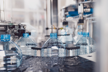 Water bottling line for processing and bottling pure spring water into bottles. Selective focus.