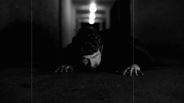Zombie crawling towards camera.  Effects added to make it look like a movie from the 1950's.  Night of the living dead style.