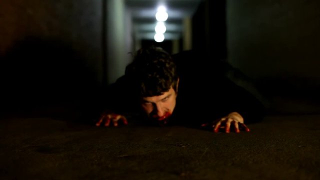 Zombie crawling through street ally in dark night scene.