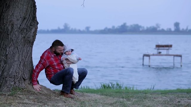 Father with baby is walking near lake
